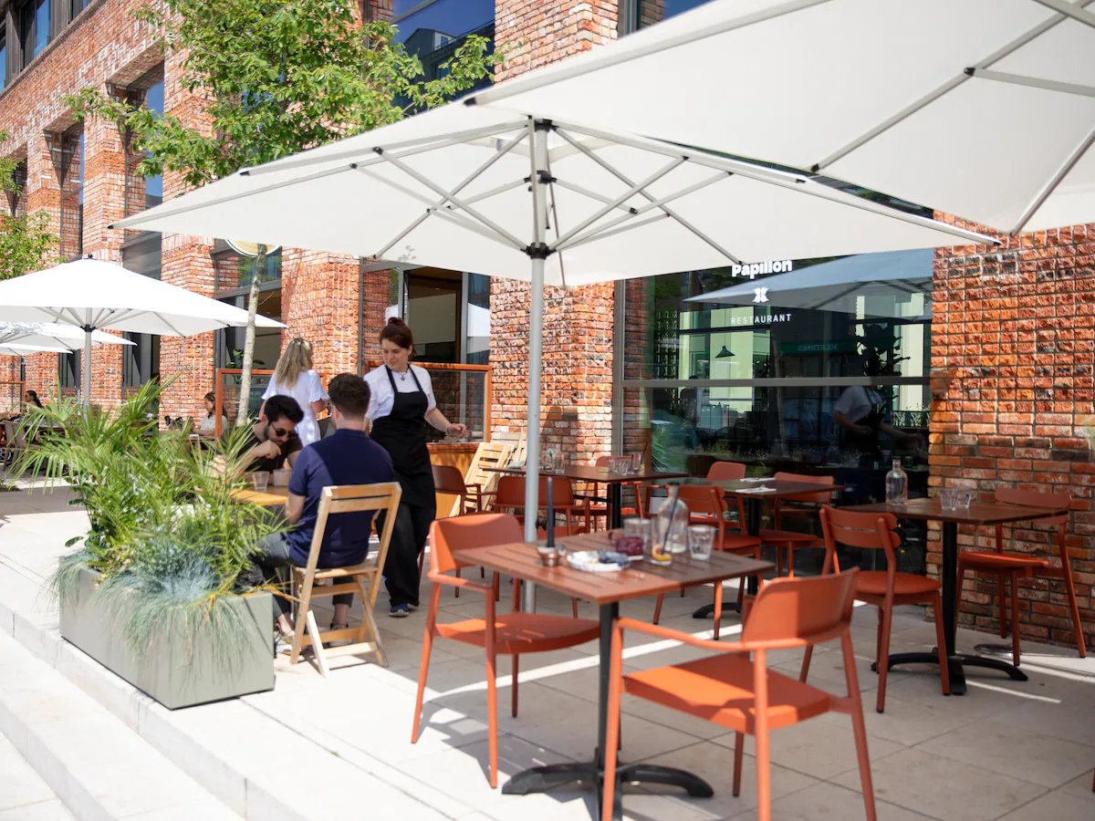 het-terras-van-restaurant-papillon-met-grote-witte-parasols